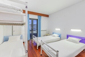 A hotel room with bunk beds, a chair, a desk, and a window with curtains. - HI Alijo - Pousada de Juventude - Hostel (Alijó)