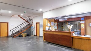 A reception desk with a wooden counter, a staircase with wooden steps, and a tiled floor.