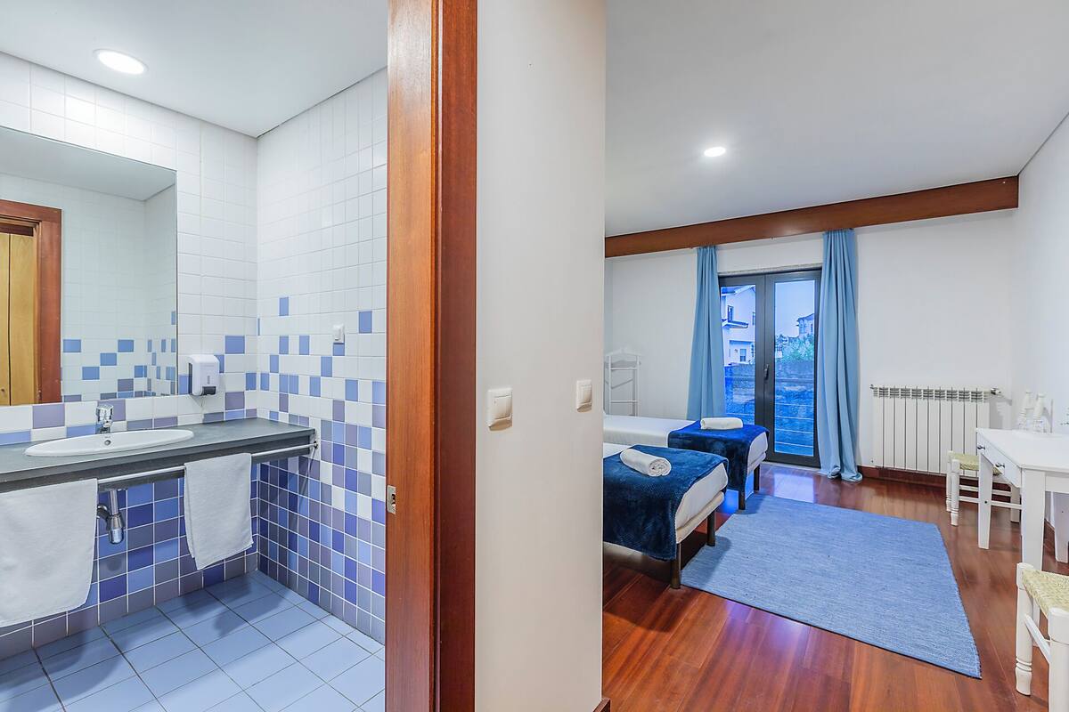 Une chambre d’hôtel avec une salle de bain, un lit, une fenêtre avec des rideaux et une vue sur l’extérieur.