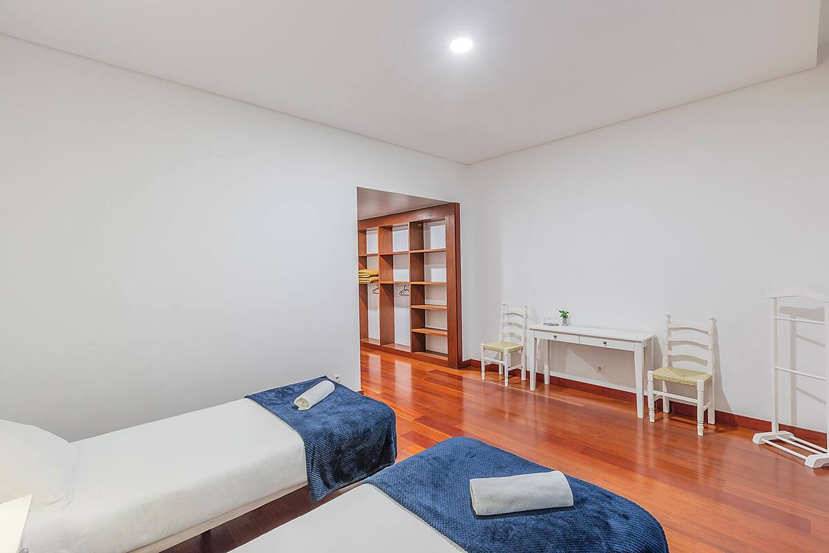 Une chambre avec deux lits, un bureau, des chaises et une armoire en bois.