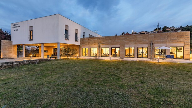 A modern building with a flat roof, large windows, and a grassy courtyard.