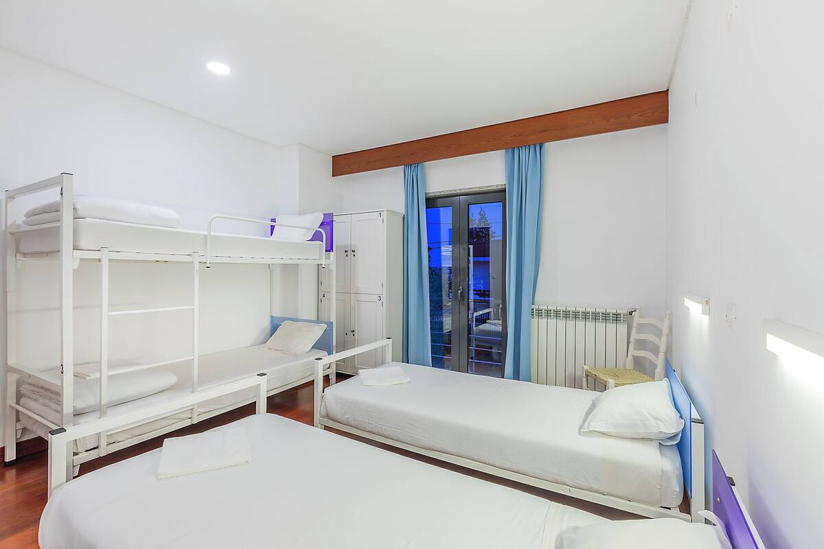 Une chambre avec des lits superposés, une fenêtre avec des rideaux et un radiateur.
