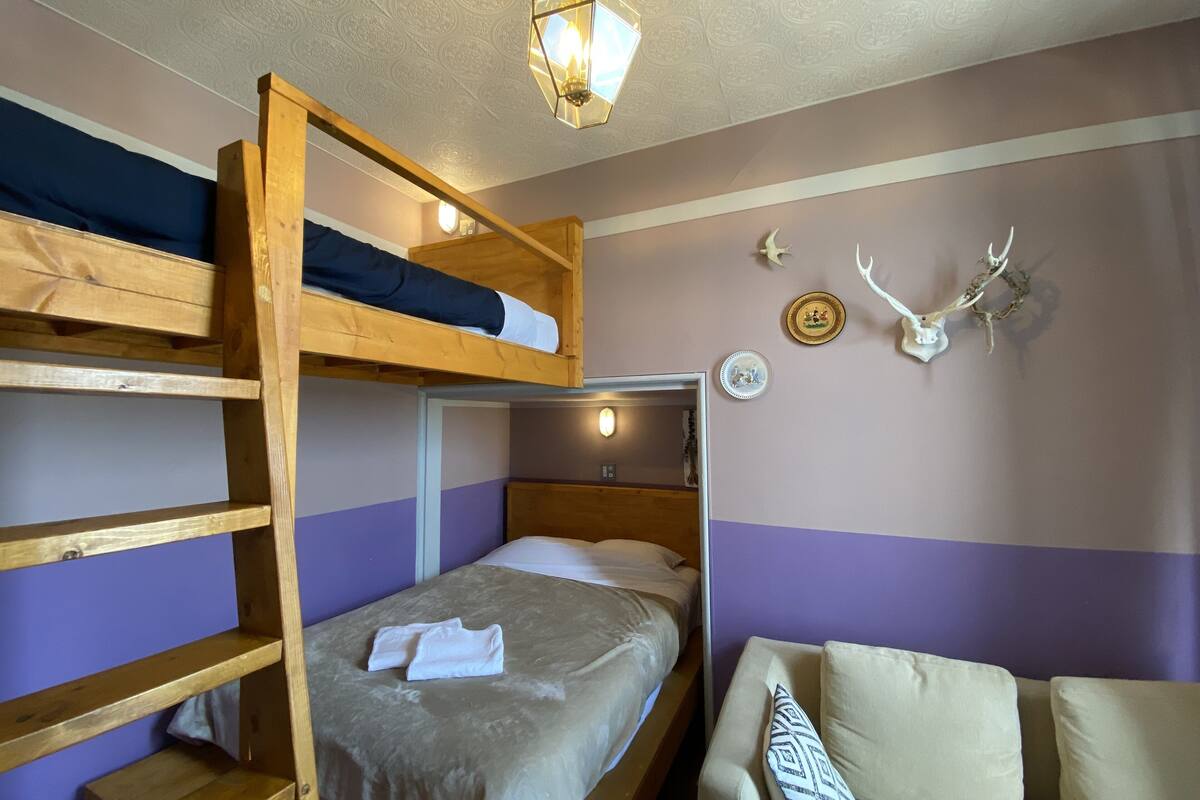 A bunk bed room with a bed, a chair, and wall decorations including a skull and antlers.