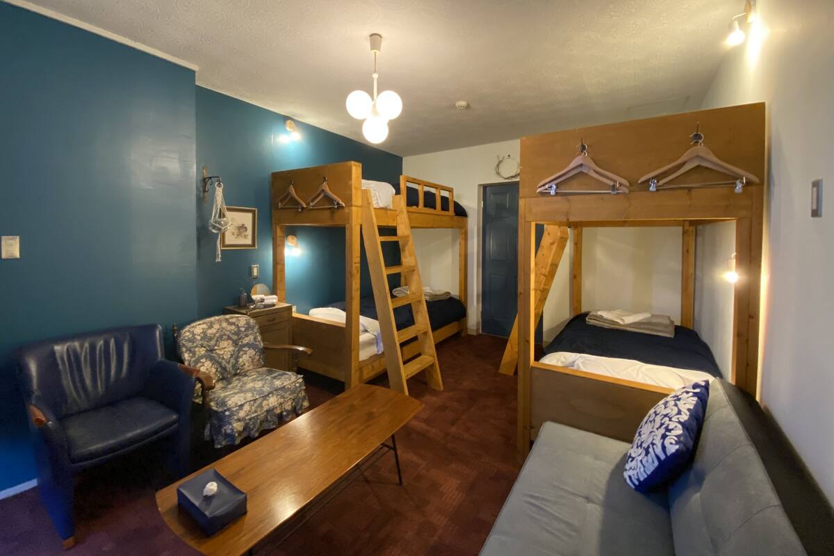 A room with bunk beds, a sofa, a chair, and a table.