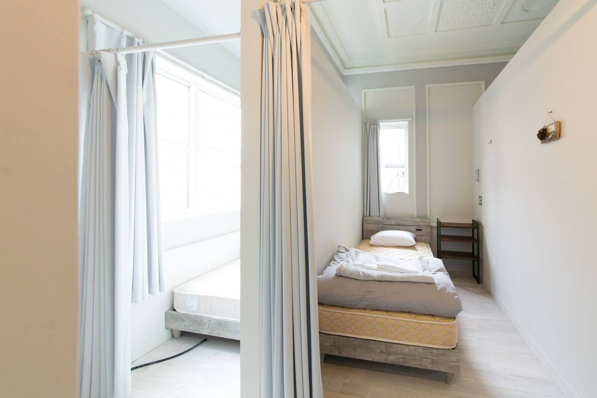 A bedroom with a bed, a window, a bedside table, and a chair.