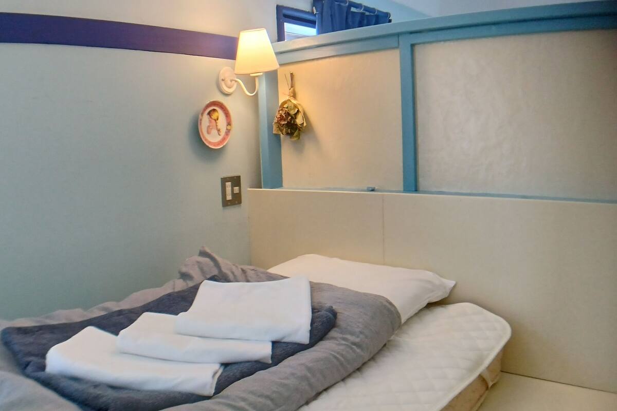 A bed with a headboard, a bedside lamp, and a wall-mounted light fixture.