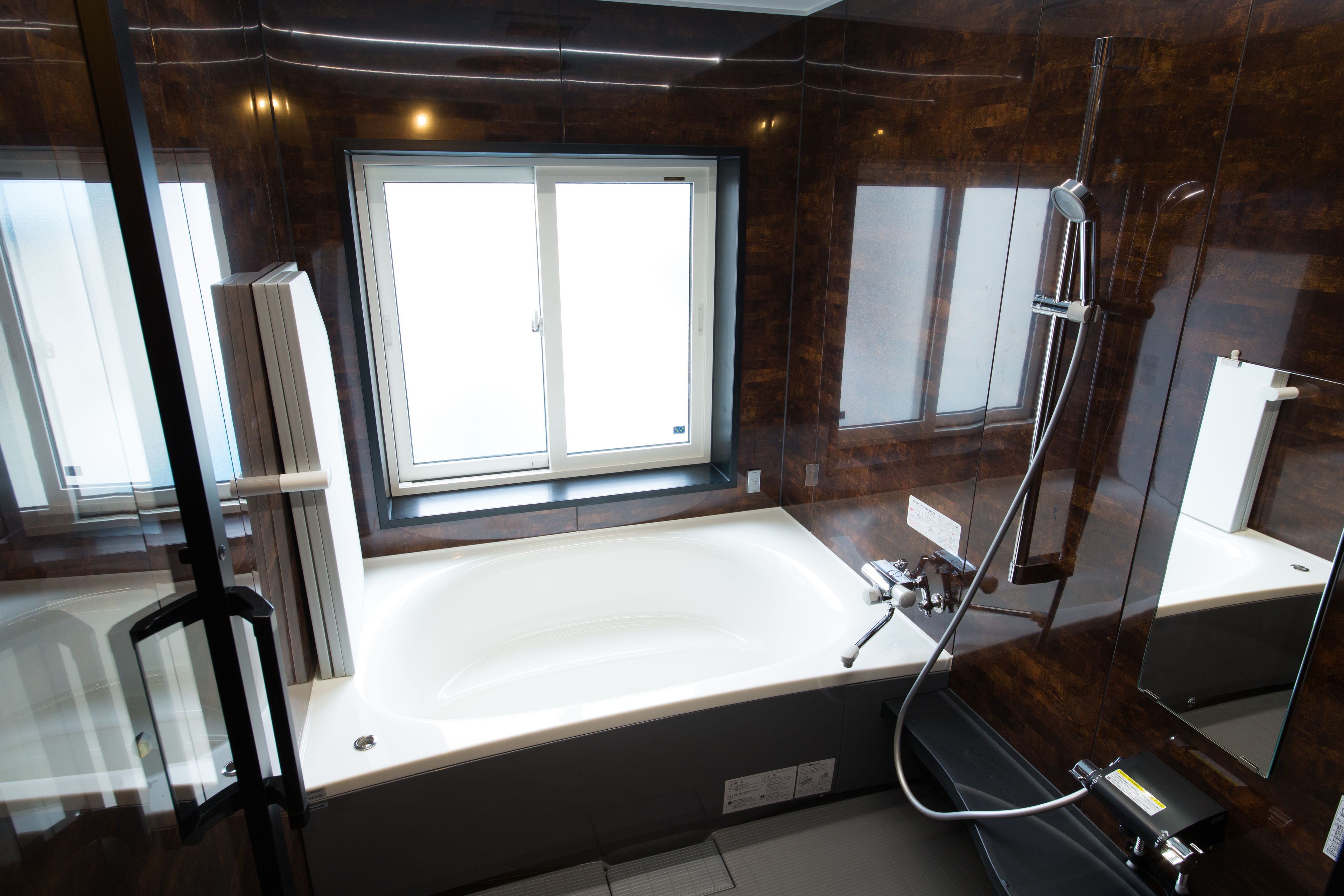 A modern bathroom with a large bathtub, a shower, and a window providing natural light.