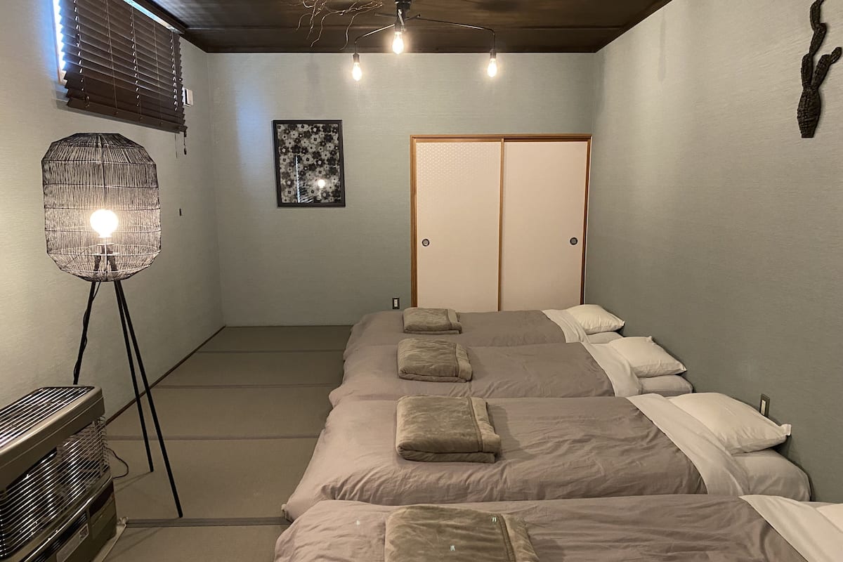 A hotel room with a large bed, a standing lamp, a heater, and a sliding door closet.