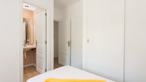 Ett hotellrum med en säng, ett badrum med handfat och en garderob.