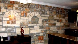 A kitchen with a stone wall, a wooden dining table, and a chandelier. - Villa Manzara (Ortaca)