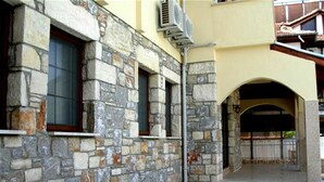 A stone building with a tiled courtyard, a potted plant, and a metal gate. - Villa Manzara (Ortaca)