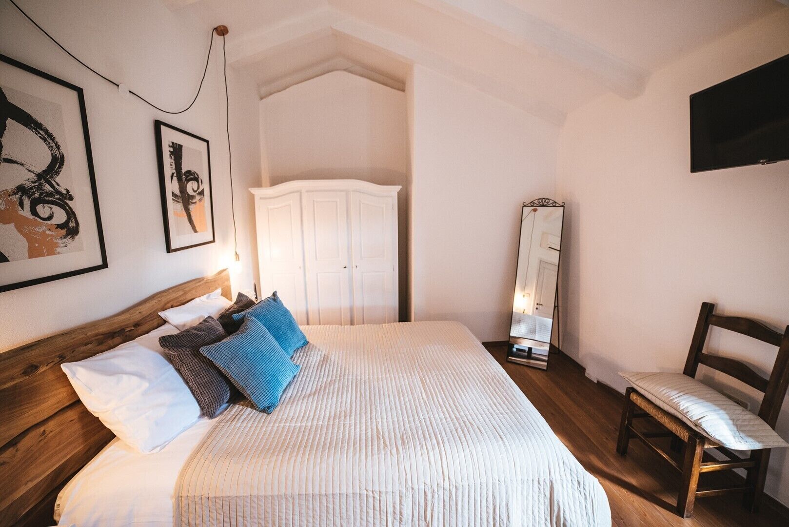 Ein Schlafzimmer mit Bett, Stuhl, Kleiderschrank und Spiegel.