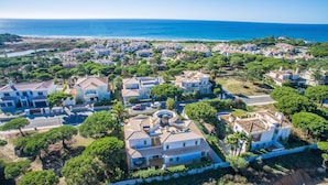 An aerial view of a coastal residential area with houses, roads, and a beach in the background. - Spacious 4 bedroom villa in quiet location with sea views  (Almancil)