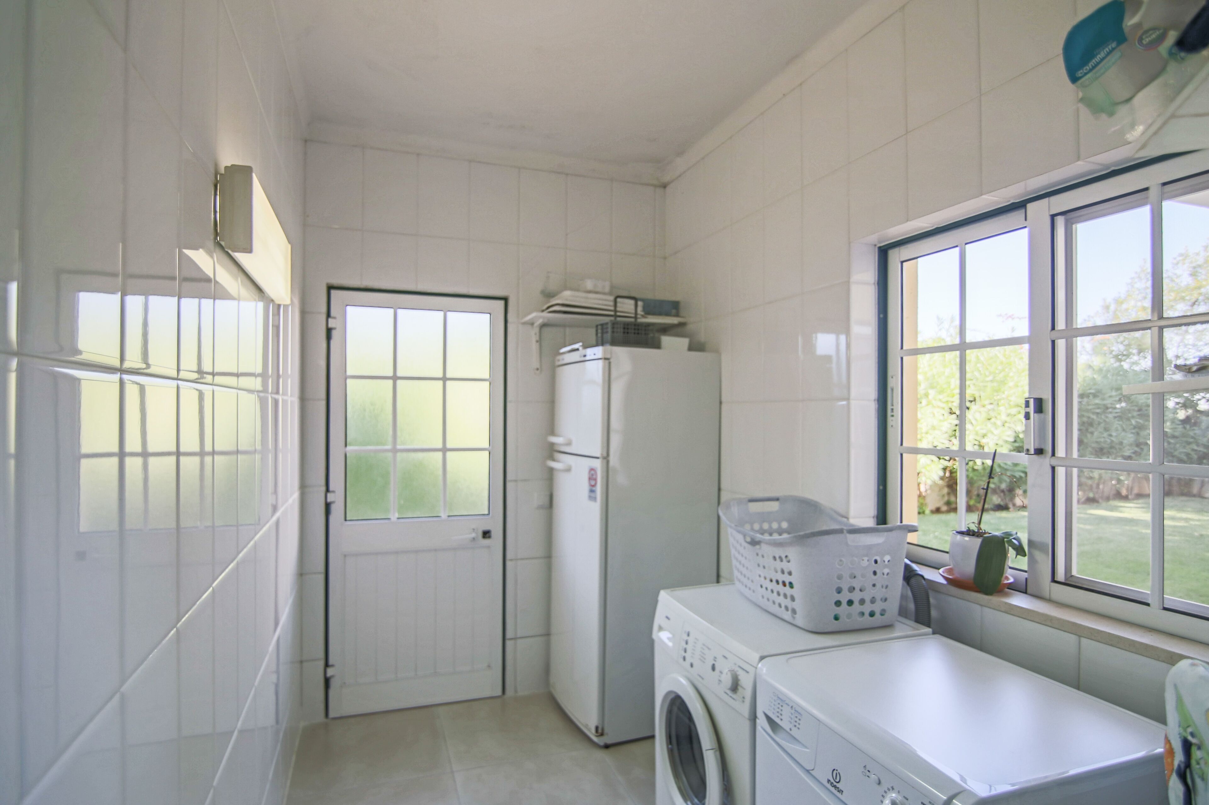 Une buanderie équipée d’un lave-linge, d’un sèche-linge et de paniers à linge empilés.