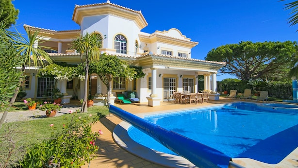 A large house with a swimming pool, surrounded by greenery and outdoor furniture. - Spacious 4 bedroom villa in quiet location with sea views  (Almancil)