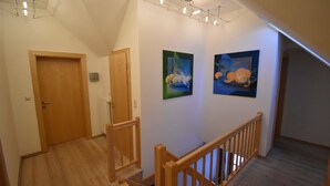 A staircase with wooden railings leading to a landing with two framed paintings. - Holiday home in a quiet location in the beautiful Carinthian Alps (Eissentratten)