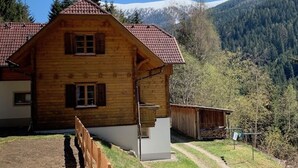 A wooden cabin with a red-tiled roof, a small porch, and a view of snow-capped mountains. - Holiday home in a quiet location in the beautiful Carinthian Alps (Eissentratten)