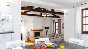 A modern living room with a fireplace, a sofa, and a dining area with a table set for two.