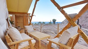 Terraza de madera con mesa y sillas, con vista a la playa.