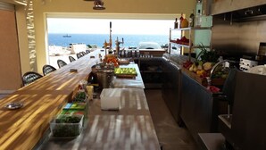 Una cocina con una encimera larga, varios electrodomésticos y vistas al mar.