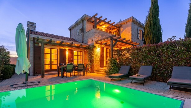 Una casa con piscina, mobiliario exterior y una pérgola.