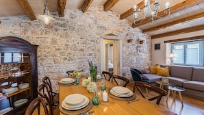 A dining area with a stone wall, wooden beams, and a chandelier. - Spacious and comfortable Villa in the heart of Barban (Grandici)
