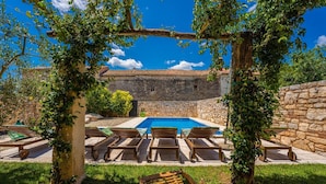 A stone building with a tiled roof, a swimming pool, and lounge chairs. - Spacious and comfortable Villa in the heart of Barban (Grandici)