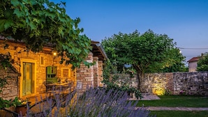 A stone building with a green door, outdoor seating, and a garden with lavender. - Spacious and comfortable Villa in the heart of Barban (Grandici)