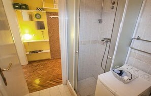 A bathroom with a shower, toilet, and a sink area.