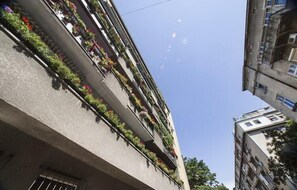 A multi-story building with balconies adorned with potted plants.