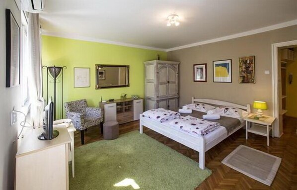 A bedroom with a bed, a desk, a wardrobe, and a mirror.