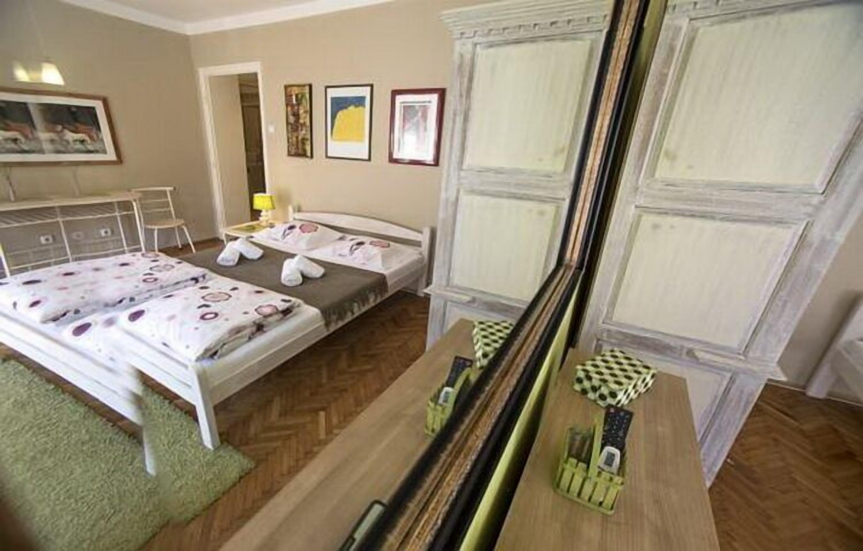 Ein Schlafzimmer mit einem Bett, einem Schreibtisch und einem Stuhl. An der Wand hängen Bilder in Rahmen.