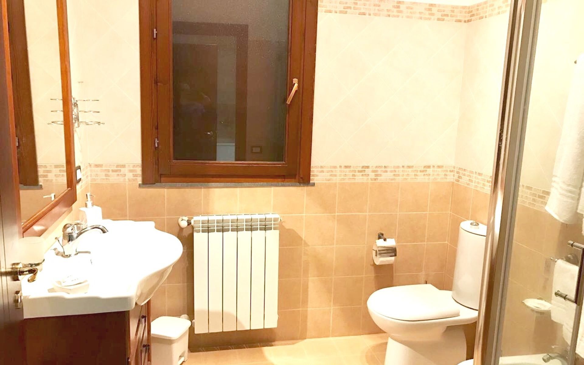 A bathroom with a sink, toilet, and a glass-enclosed shower area.