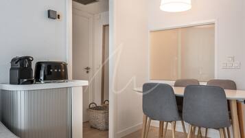 Una cocina moderna con una cafetera, una mesa de comedor con sillas y un ventanal grande.