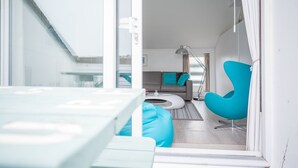 A modern living room with a sofa, a teal chair, and a coffee table. - Atlantic Blue Overlooks Porthmeor Beach in St Ives. Very Close to Town Centre, Shops, Restaurants. Free Parking. Free Wifi (St Ives)
