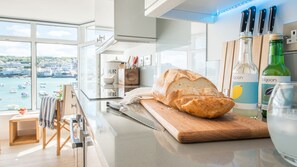 A kitchen with a loaf of bread on a cutting board, a knife, and two bottles of colgoin on the counter. - Two Harbour House, Right on the Wharf Seafront of St Ives Overlooking the Harbour and Beach. Allocated Parking in Garage. Free Wifi (St Ives)