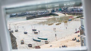 Une plage avec des bateaux, une rive sablonneuse et un mur de pierres.