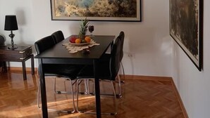 A dining area with a black table, four chairs, a fruit bowl, and a hanging light fixture. - Apartment Art Galery (Belgrade)