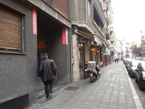 A street scene with a man walking past a closed shop with a red sign. - Apartment Art Galery (Belgrade)