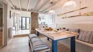 Une cuisine moderne avec une table en bois dressée pour le repas, un banc et un mur en pierre.