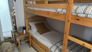 A bunk bed with a wooden frame, a bedside table with a clock, and a small plant. - Charming Studio for 4 with Balcony, Parking & Ski Storage – Near Ski Resorts (Luz-Saint-Sauveur)