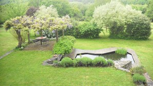 A garden with a pond, a wooden bridge, and a pergola with seating. - Tramois - Chambres d'hôtes (Donzy)