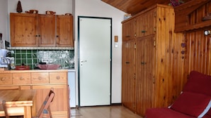Een kleine keuken met houten kastjes en een eethoek met een tafel en stoelen.