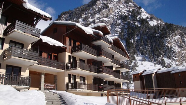 A multi-story hotel with balconies, snow-covered steps, and a mountainous backdrop. - Cozy and bright apartment, 2 rooms, near slopes, 4 people (Pralognan-la-Vanoise)
