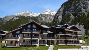 A multi-story hotel with balconies, set against a backdrop of snow-capped mountains. - Cozy and bright apartment, 2 rooms, near slopes, 4 people (Pralognan-la-Vanoise)
