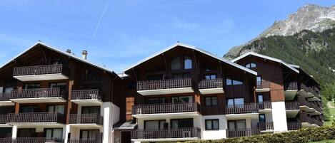 Ein mehrstöckiges Holzchalet mit Balkonen vor einer Bergkulisse.