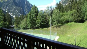 Eine gebirgige Landschaft mit Tennisplatz und Zaun.