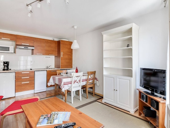 Um espaço compacto com cozinha compacta, área de refeições e sistema de entretenimento.