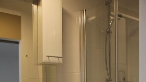 A modern bathroom with a glass-enclosed shower, a sink with a mirror, and a towel rack. - Appartement- Steinkirchner (Straubing)