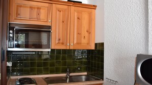 A kitchen with wooden cabinets, a microwave, a sink, and a Siemens dishwasher.